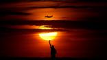 A plane flying past the Statue of Liberty